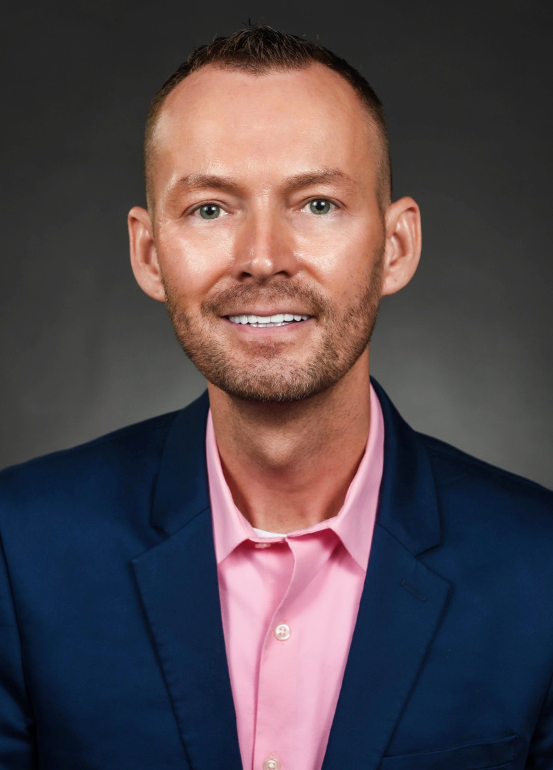 Chris Noble in a dark blue suit and pink shirt