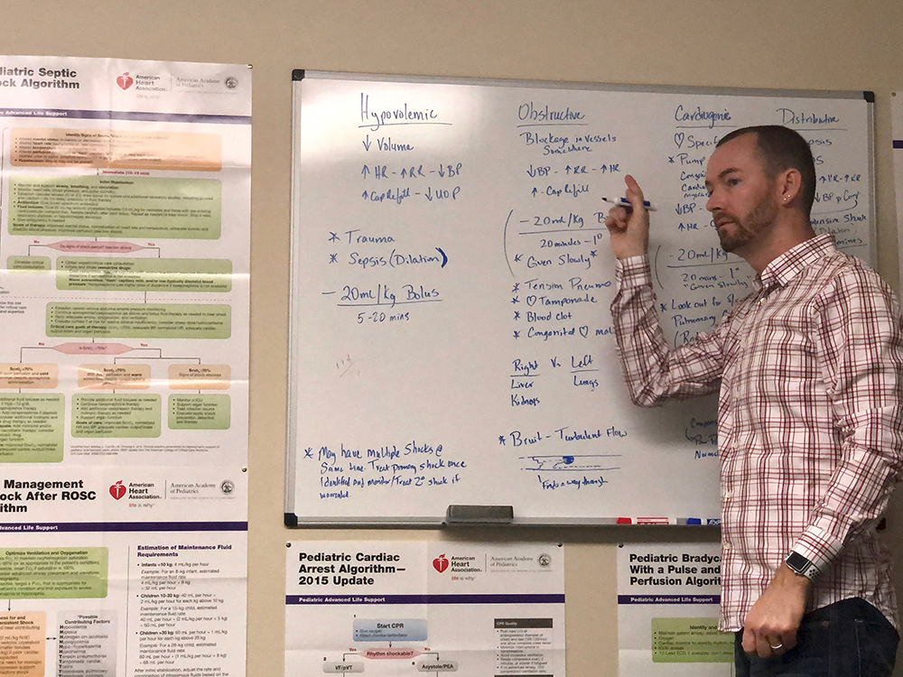 A photo of Chris Noble standing in front of a whiteboard teaching a class.